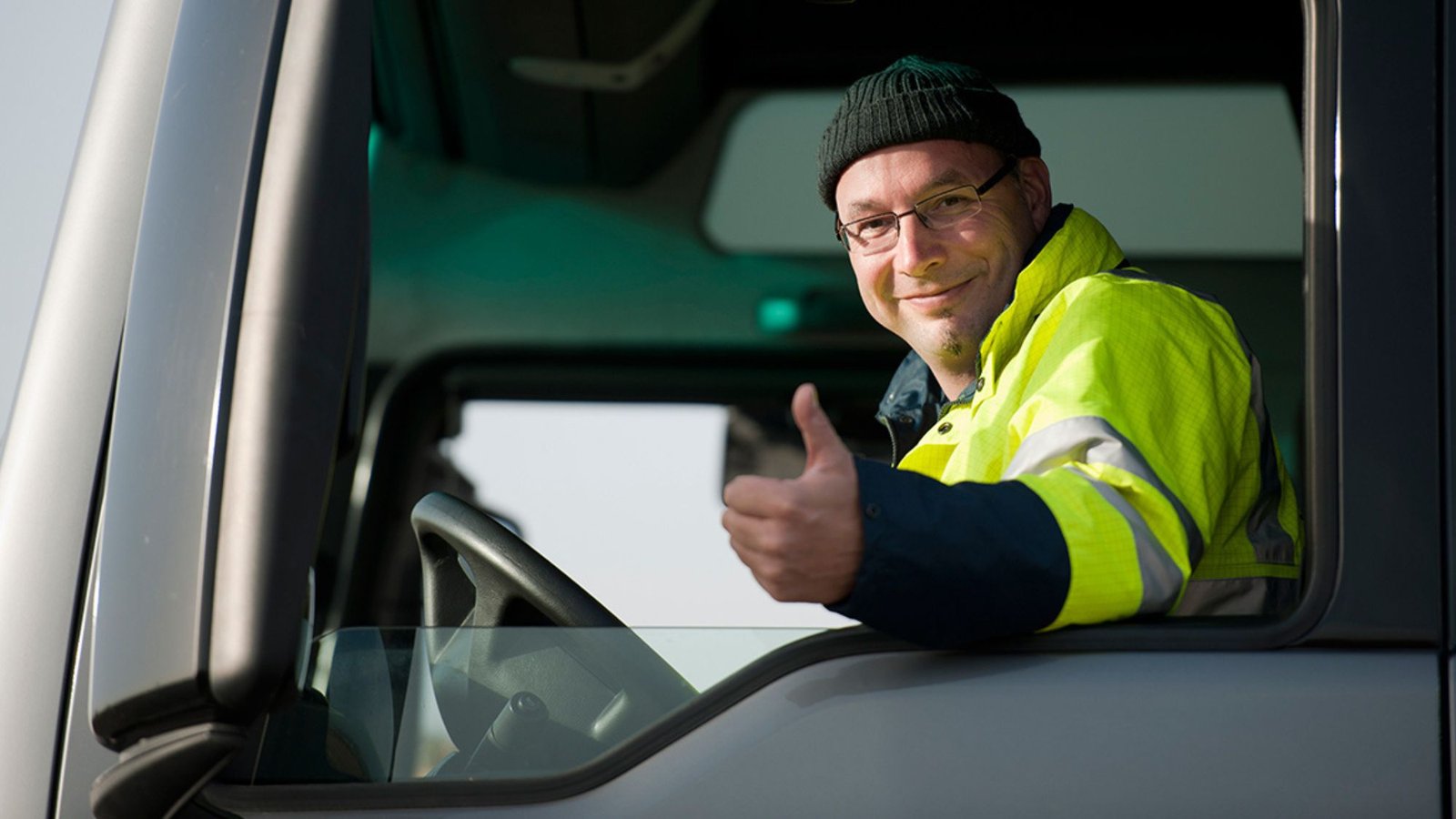 A truck driver showing thumbs up & endorsing regular vehicle checks are crucial for a safe driving